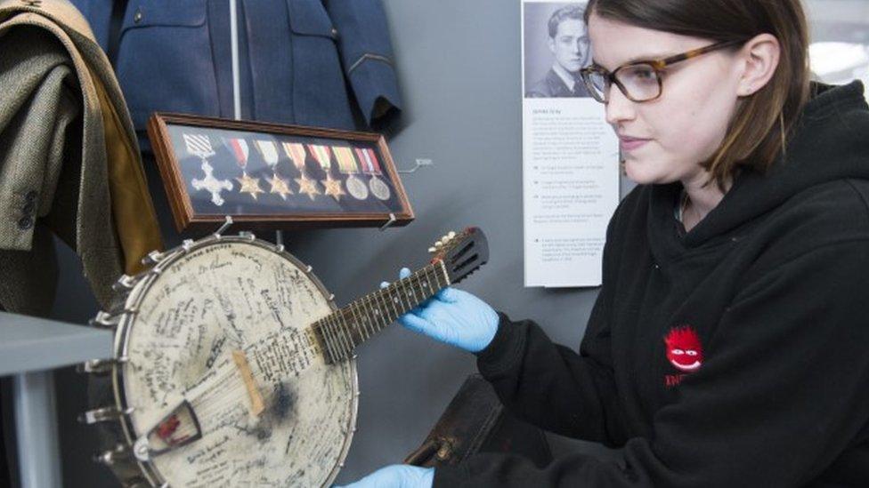 A museum worker holds a signed banjo