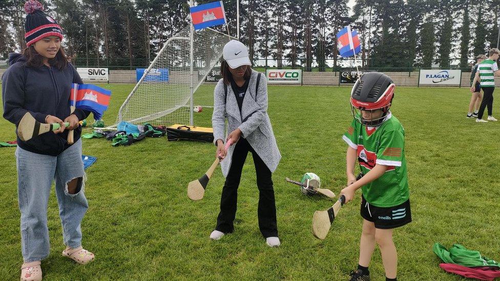 A young Michael Davitt GAC player teaches a member of Cambodia's Cairde Khmer how to play hurling