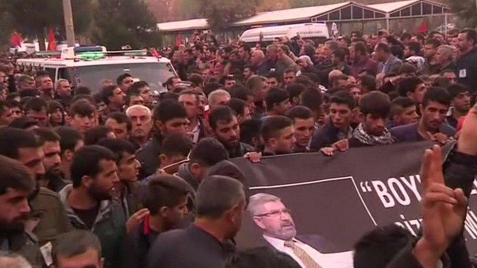 Thousands march carrying a banner showing Tahir Elci