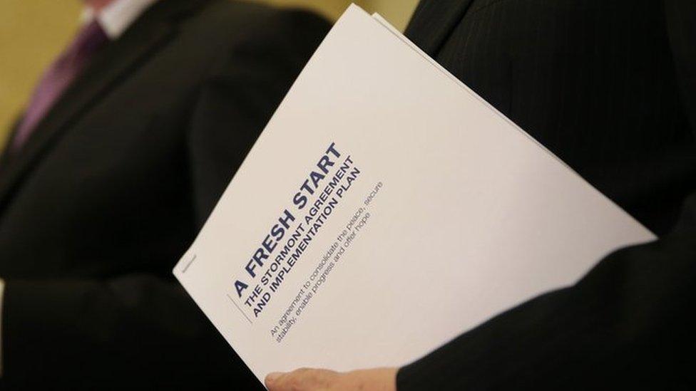 First Minister Peter Robinson holds a copy of the agreement as he speaks alongside Deputy First Minister Martin McGuinness