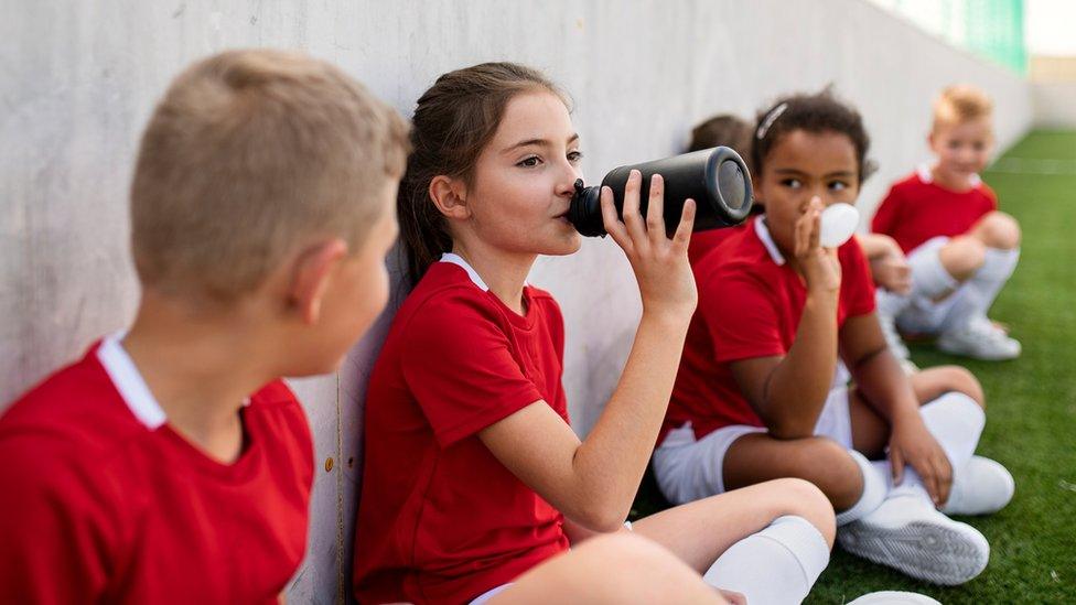 Children taking a break whilst playing football