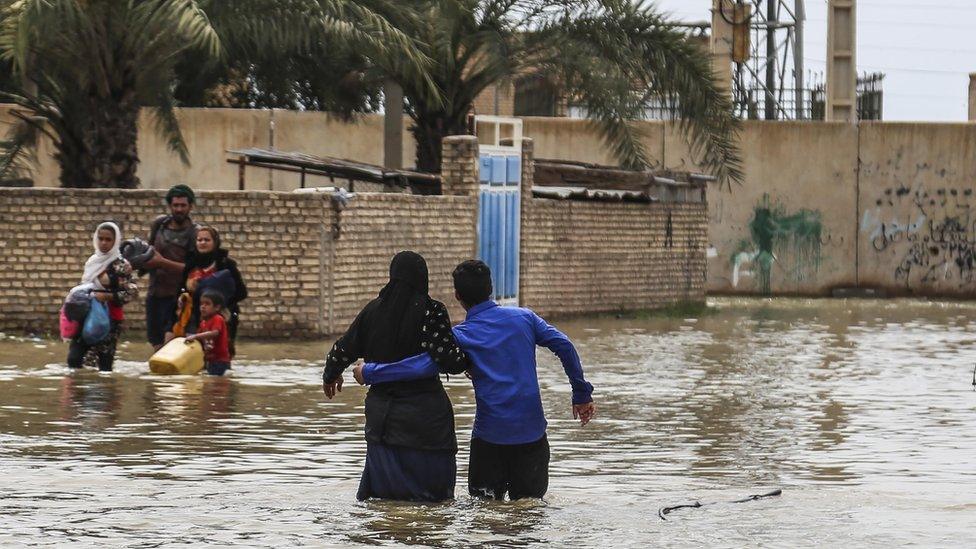 Iranians walk through floodwaters after unprecedented rains, March 2019