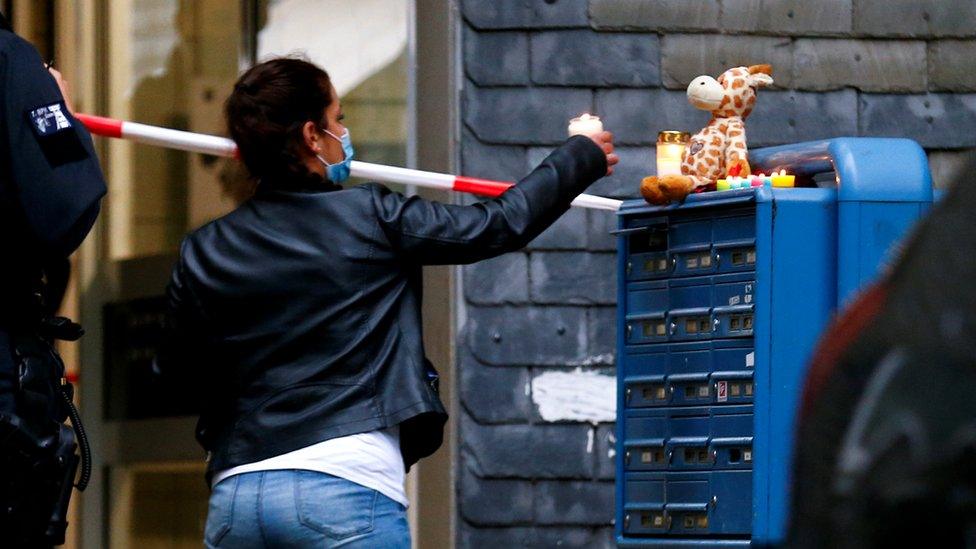 A woman places a candle outside the residential building where the bodies of five children were found in the western town of Solingen, Germany, 3 September 2020