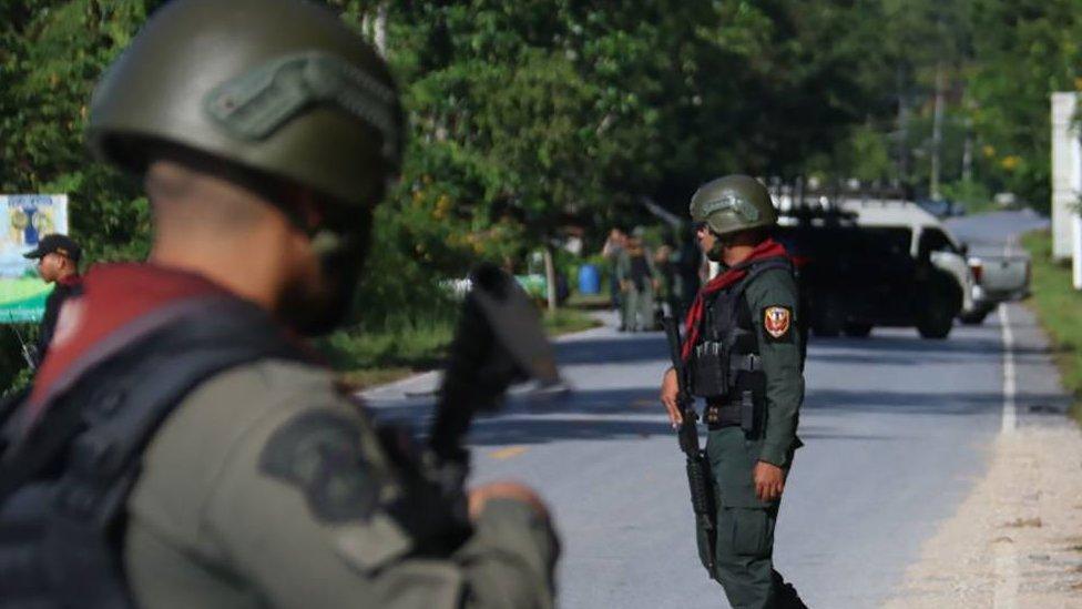 Members of a bomb squad inspect the site of an attack by suspected Muslim militants