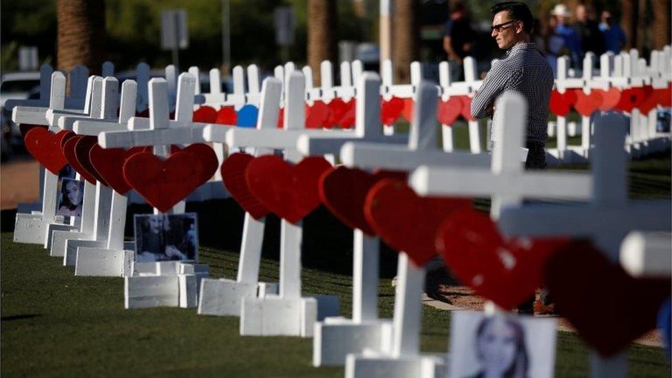 A man looks at the 58 white crosses displayed for the victims of the Route 91 music festival shooting in Las Vegas, Nevada.