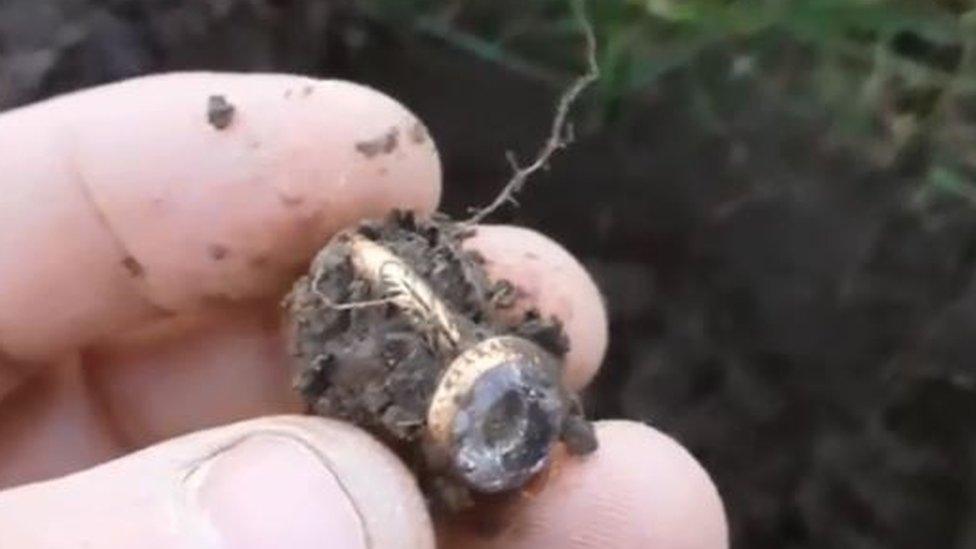 Hand holding the ring after it has been taken out of the ground