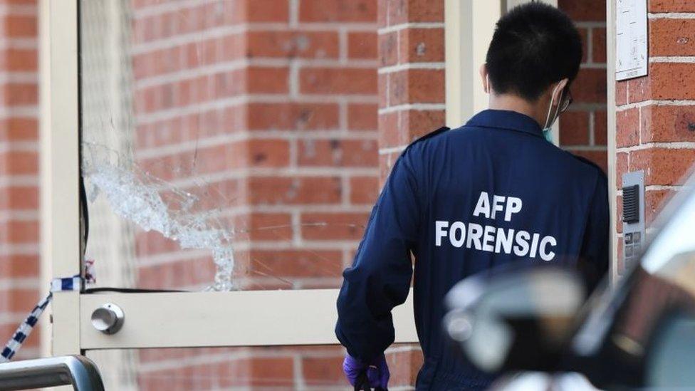 An Australian Federal Police forensic investigator enters a Sydney house being searched as part of the probe