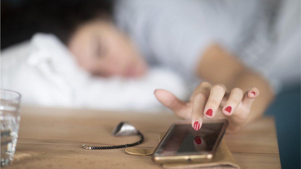 A woman tapping her phone alarm