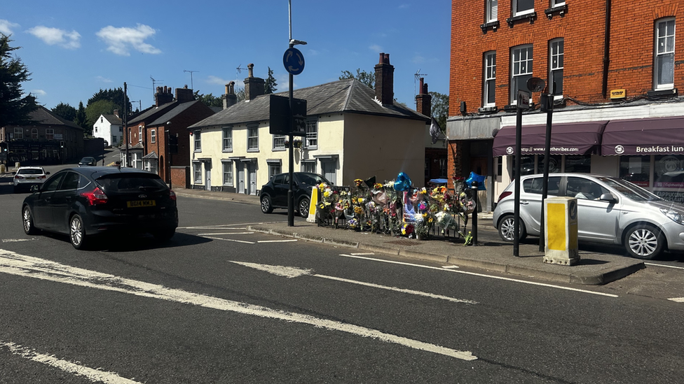 Flowers and a photo of Lucas Pollard left by railings at a road junction