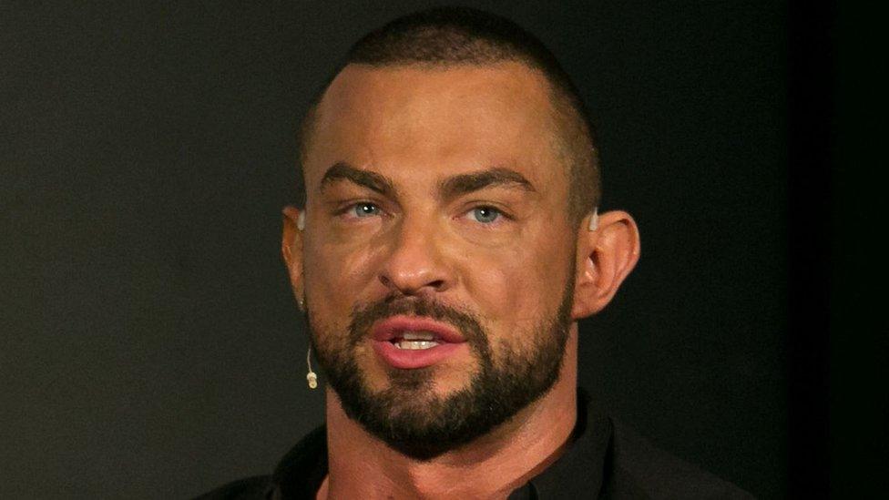 Robin Windsor wearing a black top. He is wearing a headset on his right ear and had a beard.