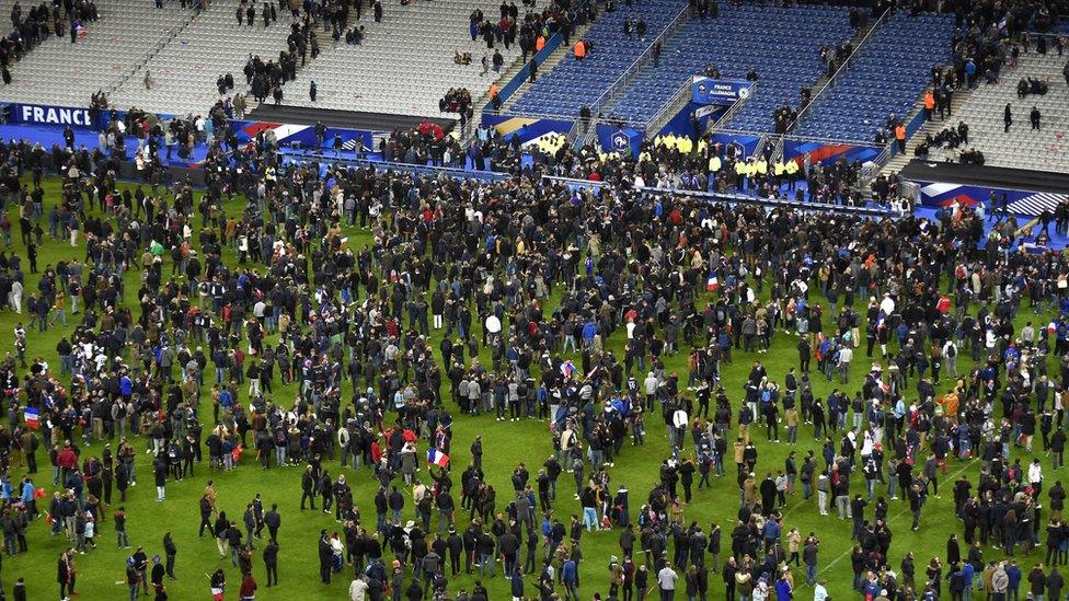 Football fans gather in the field as they wait for security clearance to leave the Stade de France in Saint-Denis, north of Paris, after the friendly football match France vs Germany on November 13, 2015 following shootings and explosions near the stadium and in the French capital