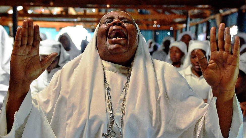 A woman praying in church in Kenya - archive shot