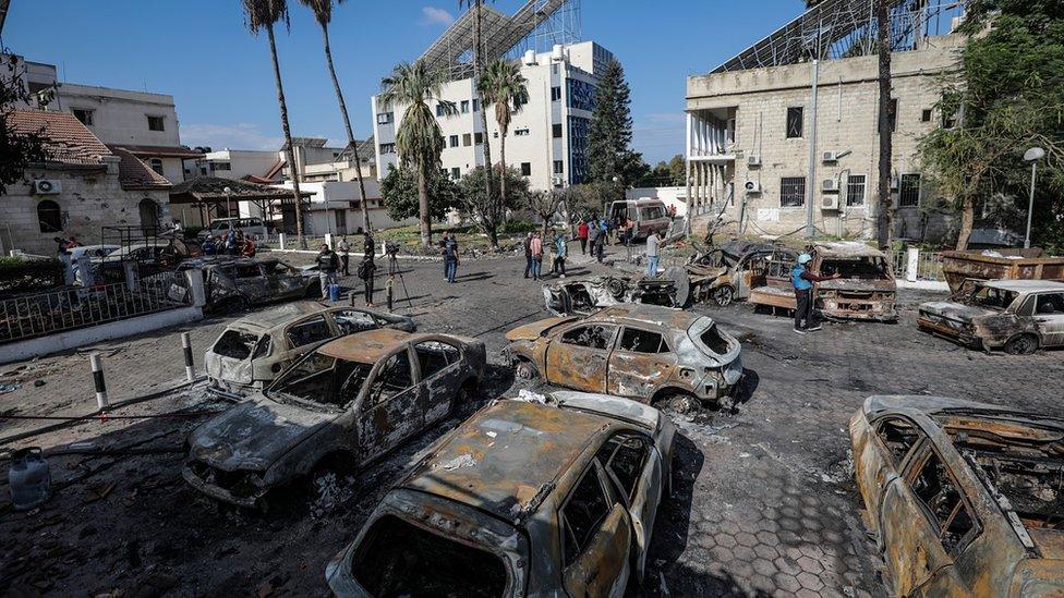 People walk in the courtyard of the Al-Ahli Arab hospital in Gaza City, where hundreds of people were reportedly killed by an explosion (18 October 2023)