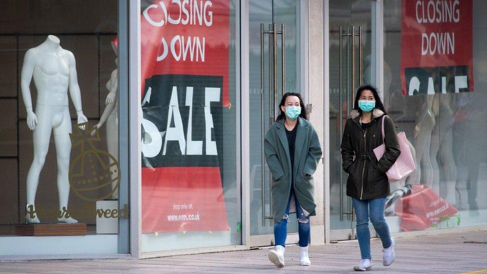 two women walking past closed shop