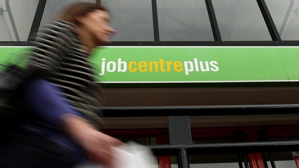 A woman walking past a job centre plus building.