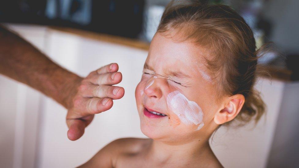 Girl having sunscreen applied