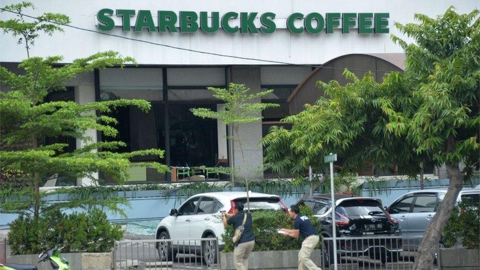 Plainclothes police aim their handguns towards suspects outside a cafe after a series of blasts hit the Indonesia capital Jakarta on January 14, 2016.