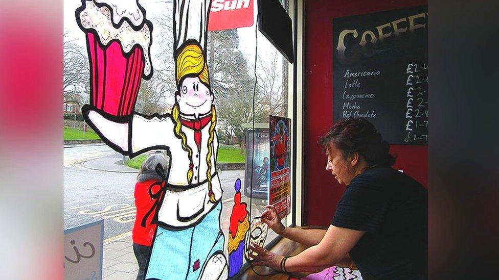 A woman working on window art