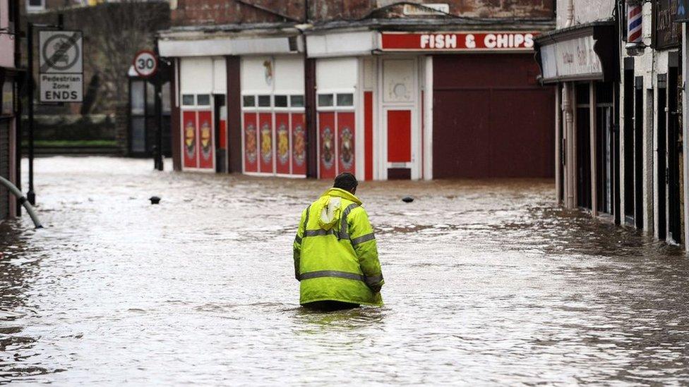 A man wades through floodwater in a street in Dumfries