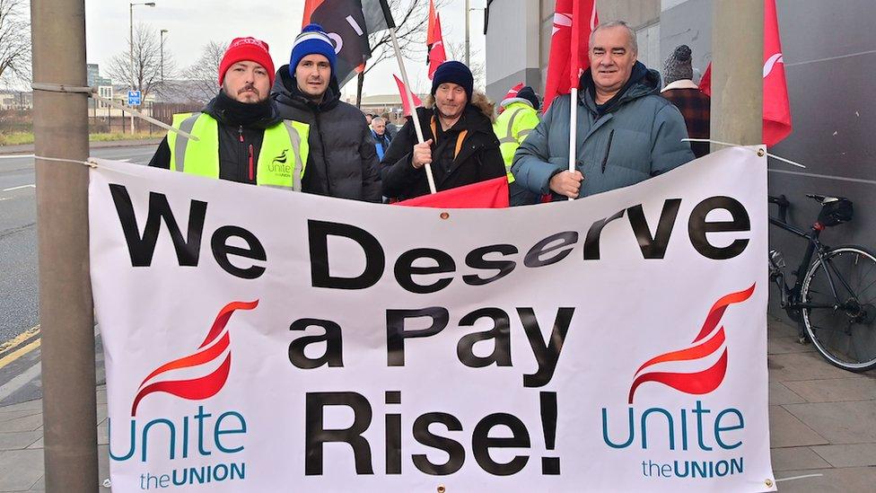 Striking Translink workers with a 'We Deserve A Pay Rise' sign