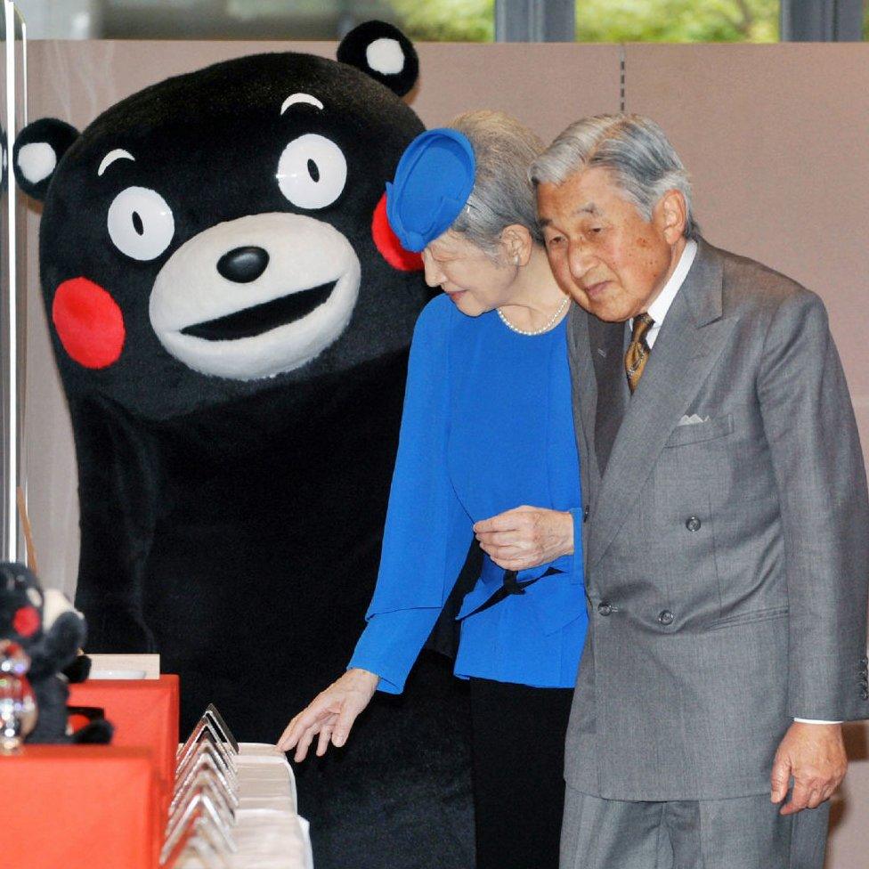 Japanese Emperor Akihito (R) and Empress Michiko (C) stand next to 'Kumamon' (L)