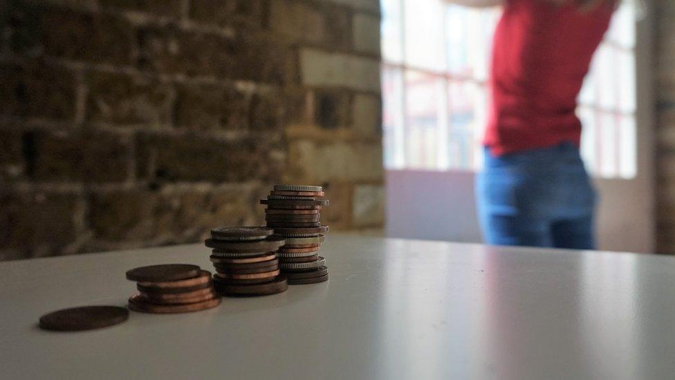 Piles of coins and woman standing in the background