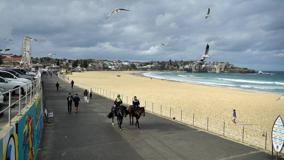 Police on horseback pass Bondi Beach