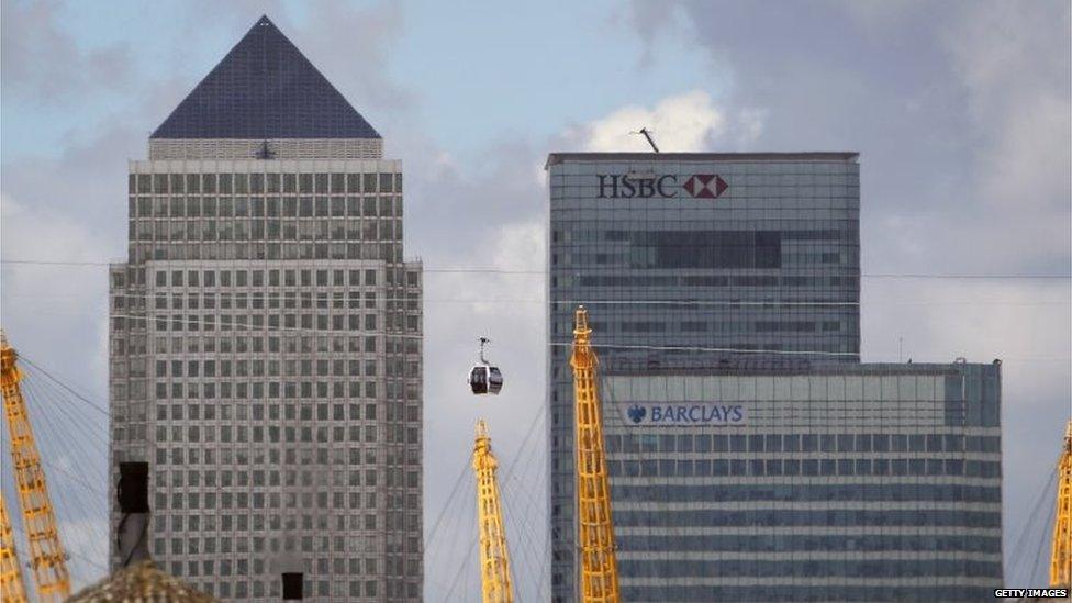 Transport for London (TfL) Emirates Air Line cable car passes over the River Thames in front of the Canary Wharf business district