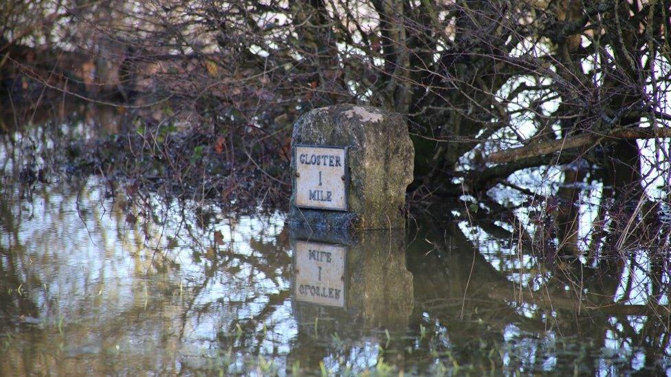 A sign of Gloucester with flood water high up against it