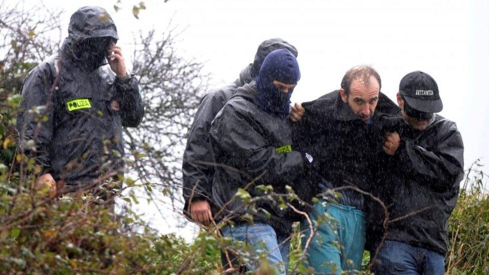 Basque police lead suspected leader of an ETA cell away from an arms and explosives hide ollowing a search in woods near the fishing town of Ondarroa, Spain (29 January 2010)