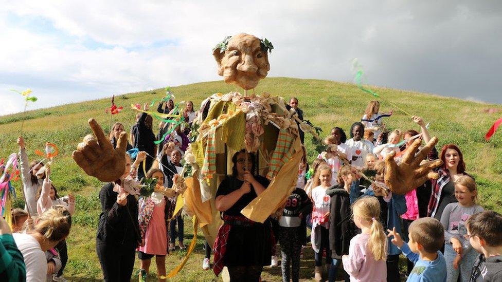 The Work Furnace project in a procession with banners, props and puppets