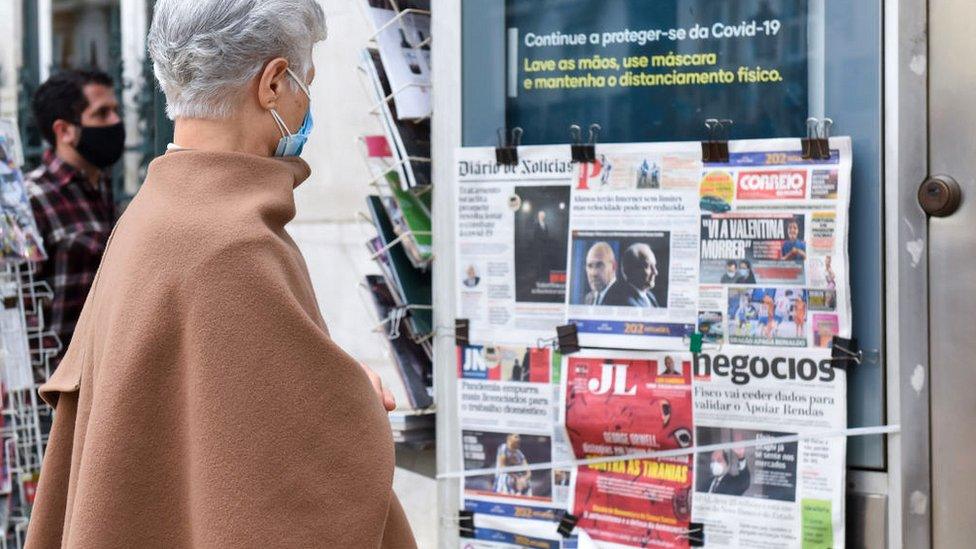 A woman reads the newspapers frontpages at a newsagent