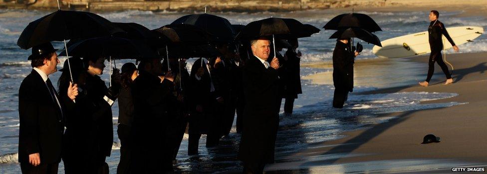 Malcolm Turnbull and others hold umbrellas in an art installation at Bondi beach, Sydney, Australia