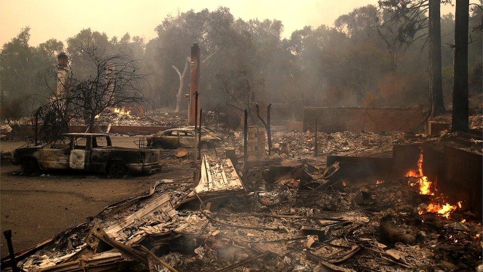 Burned out wreckages of houses and cars are pictured