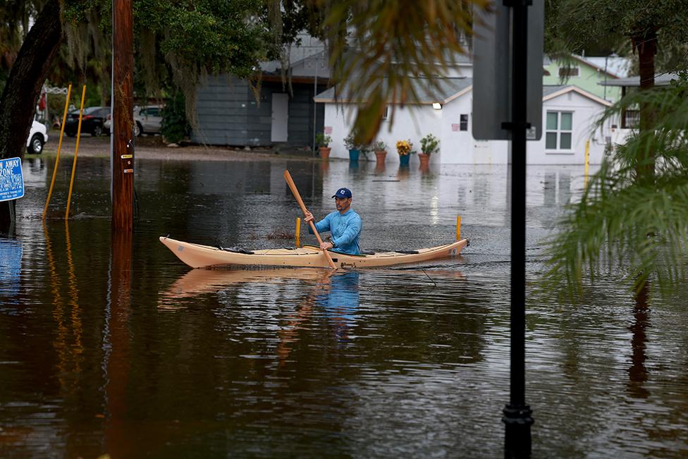 A person rides a kayak through the flooded streets caused by Hurricane Idalia passing offshore on 30 August 2023 in Tarpon Springs, Florida