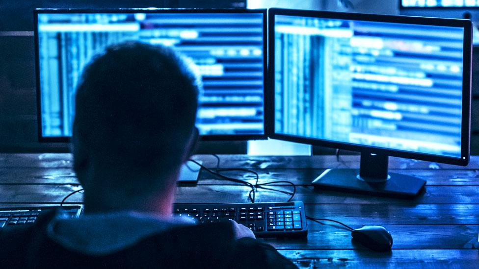 A stock image of a man using a computer with two screens