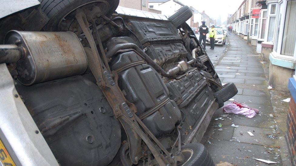 Car on side after crashing into house