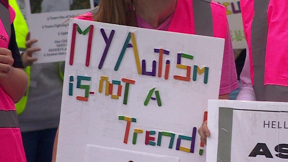 sign at a protest that reads "my autism is not a trend"