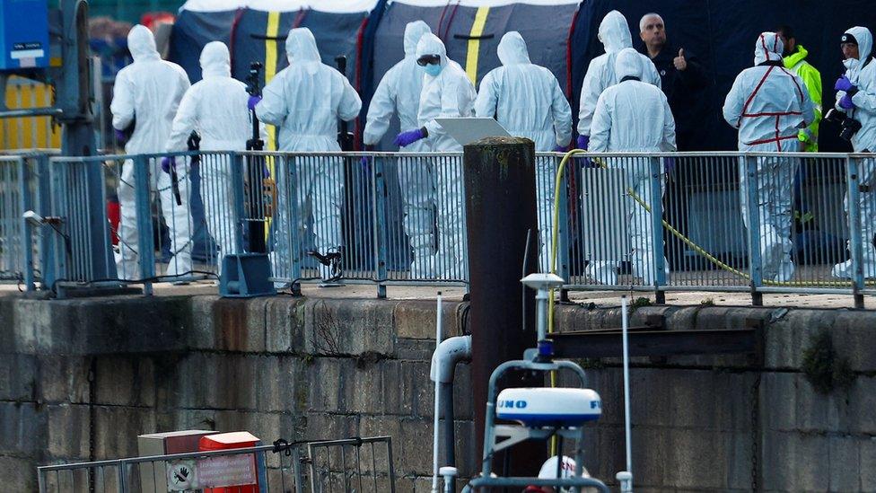 Police forensics officers wearing protective gear walk at the Port of Dover