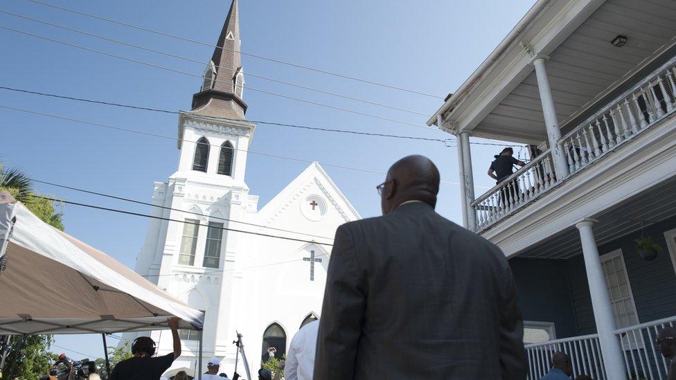 2015-06-21. Members of the community gathered in front of Emanuel AME Church in Charleston Sunday. Colm O'Molloy for BBC News.