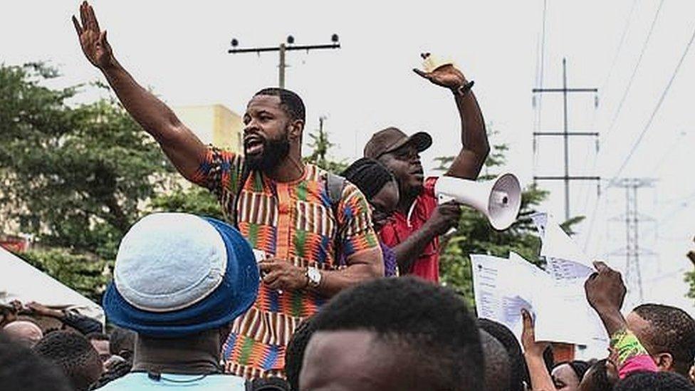 Two men speaking through loudspeakers to a crowd