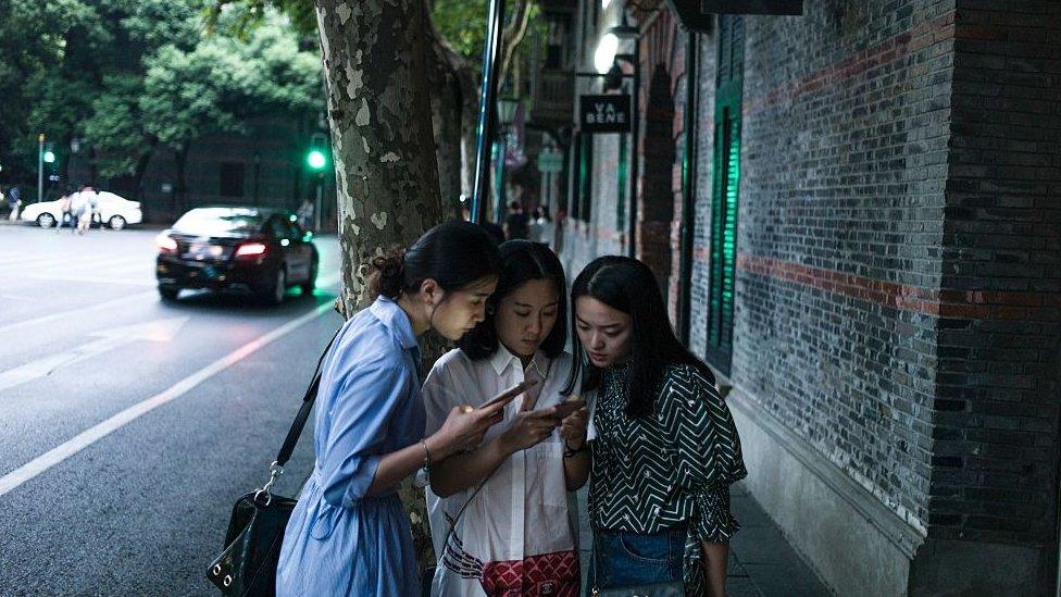 Women look at their smartphones in Xintiandi district, a shopping area, in Shanghai on September 8, 2016.