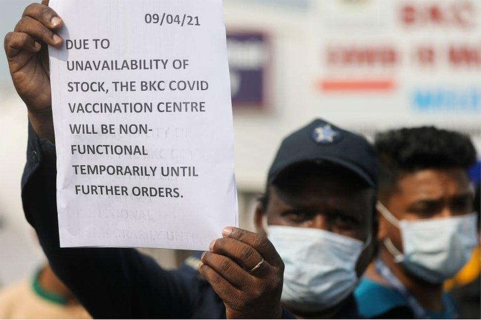 A guard holds up a notice to inform people about the shortage of coronavirus disease (COVID-19) vaccine supplies at a vaccination centre, in Mumbai, India, April 9, 2021.