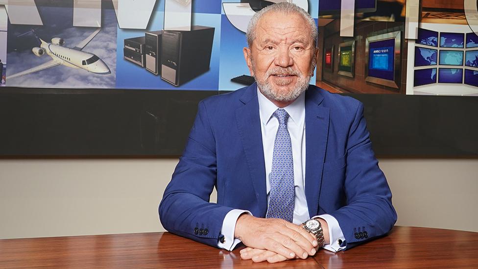 Alan Sugar wearing a suit and tie in his boardroom