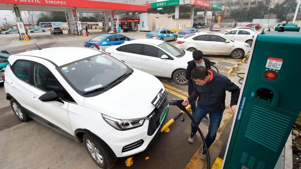 This photo taken on January 14, 2019 shows a man plugging in an electric vehicle at a Sinopec service station in Hangzhou, in China's eastern Zhejiang province.