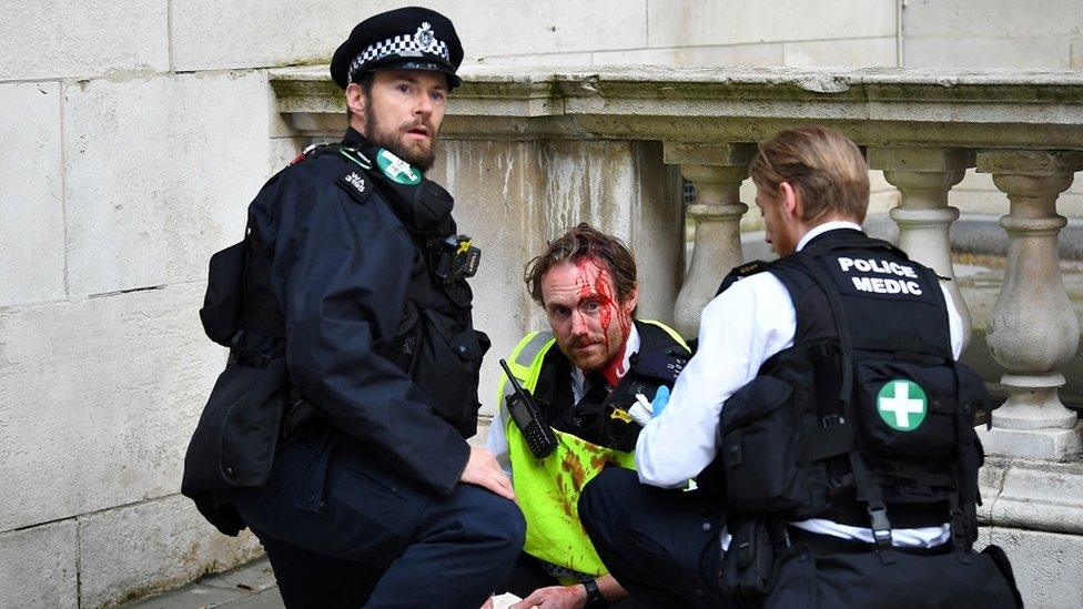 A Police officer receives medical attention after Police clash with demonstrators on Whitehall during a Black Lives Matter protest in London