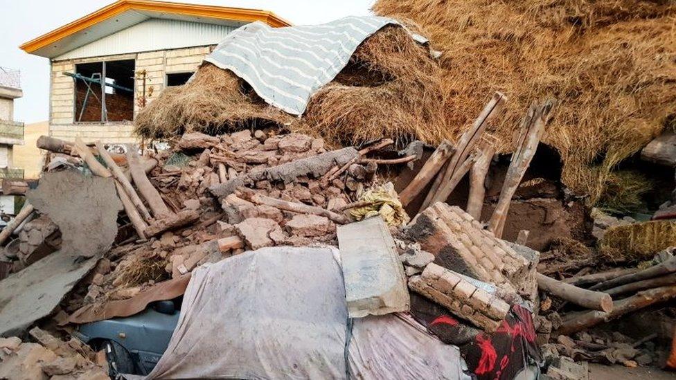 A damaged car is seen under the ruins in Varnakesh village on 8 November