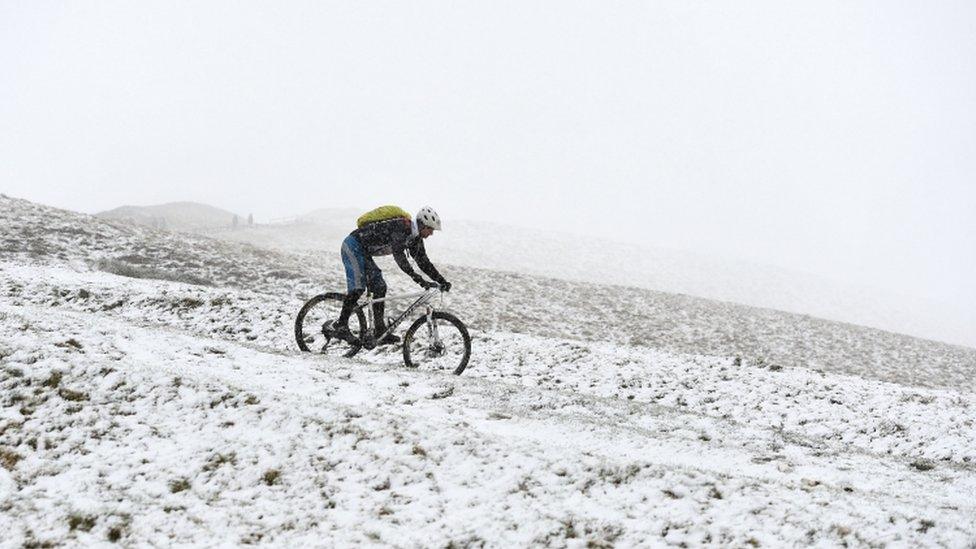 A cyclist in the snow in Mam Tor hill in the Peak District