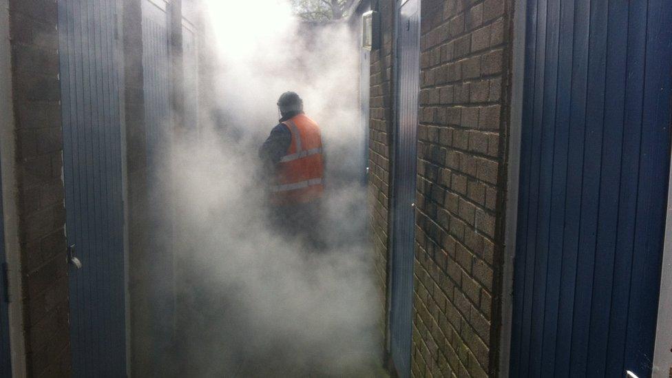 A council employee using high-pressure water to remove graffiti