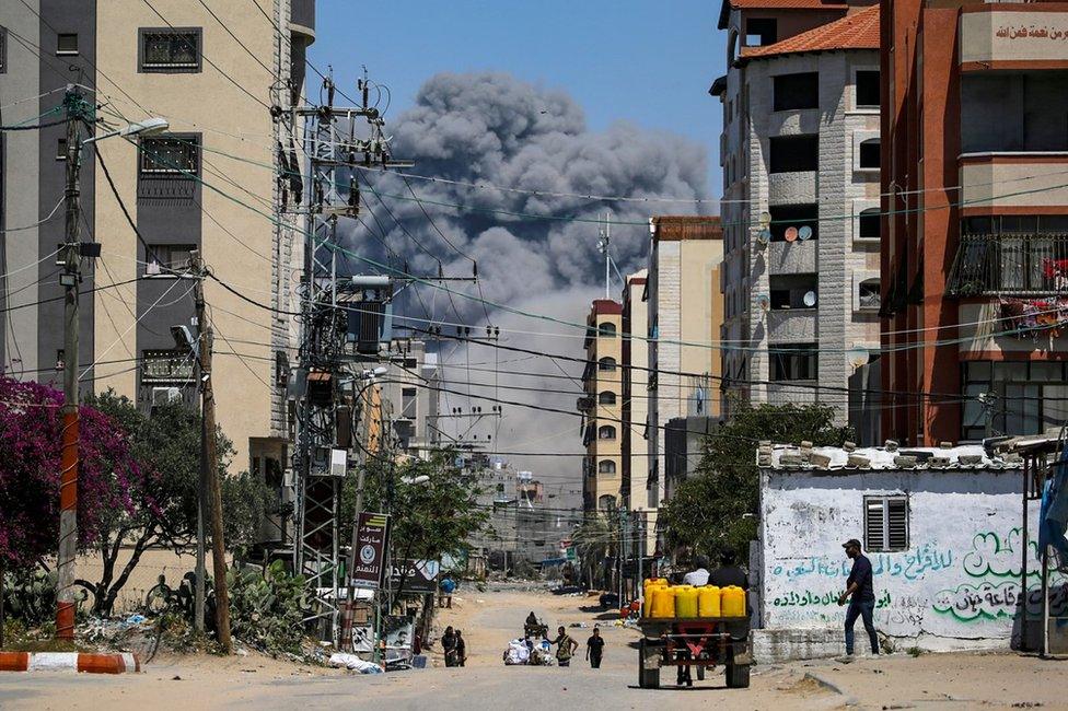 Palestinians flee as smoke rises following an Israeli air strike during an operation in Nuseirat refugee camp, central Gaza (17 April 2024)